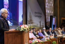 Srinagar SKICC conference hall with LG at podium addressing audience, inter-faith leaders seated, emotional anti-drug campaign awareness event in Jammu and Kashmir, wide landscape news-style photo.